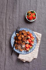 Fototapeta na wymiar Mini chocolate pancake cereal with strawberries for breakfast on gray old textile tablecloth. Trendy home breakfast with tiny pancakes. Top view