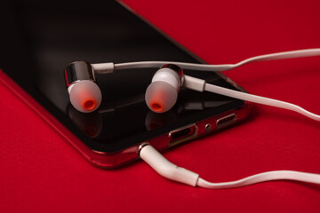Telephone on a red background. The phone has white headphones.