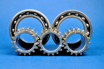 Metal gears and roller bearings on a blue background. Spare parts.