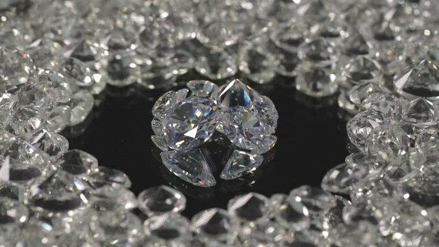 .diamonds in different shape and different size place on center of circle on mirror are spinning around in black background.