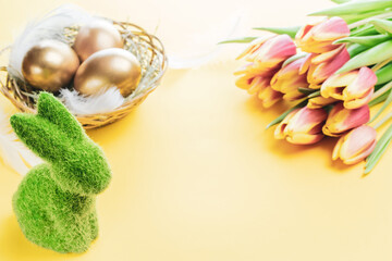 Naklejka na ściany i meble Easter eggs Golden color in basket with spring tulips, white feathers on pastel yellow background in Happy Easter decoration. Festive decoration.