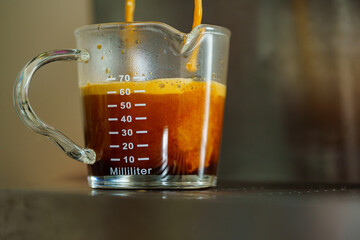 Close up and macro crema coffee shot A coffee espresso machine pouring in the coffee mug glass single and double shot by barista in coffee shop cafe.