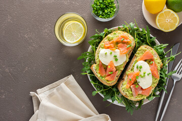 Delicious hearty breakfast, sandwiches with avocado paste, salmon and mozzarella on a plate with arugula and pea sprouts