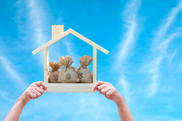 Woman hand holding show a label of home model with money bag  working capital management on Blue...