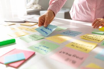 Business woman working on a project using sticky notes on her desktop. Brainstorming to find new development ideas and company strategies.