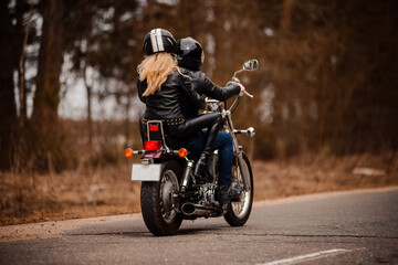 A couple of bikers a girl and a guy ride on the same motorcycle on the road