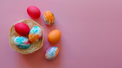 Happy Easter holiday! Colorful hand-painted Easter eggs in a decorative nest on pink background.