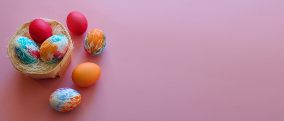 Fototapeta na wymiar Happy Easter holiday! Colorful hand-painted Easter eggs in a decorative nest on pink background.