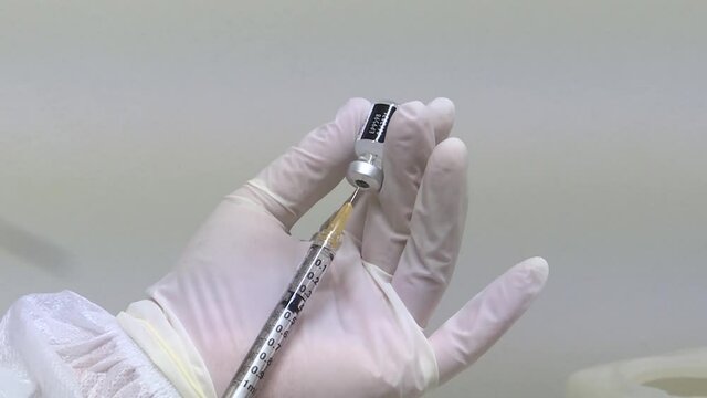 Hand of a doctor preparing a siringe with the Covid-19 vaccine for inoculation.