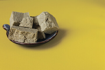 Pieces of sunflower halva from seeds on a yellow background. Space for text