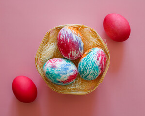 Happy Easter holiday! Colorful hand-painted Easter eggs in a decorative nest on pink background.
