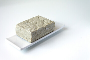 One piece of sunflower halva on a light background. Space for text