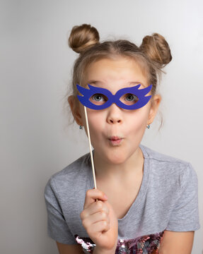 Little girl with surprised facial expression wearing paper glasses masquerade mask studio portrait. Amazed female child with surprise on his face. Delighted child in a beautiful mask. Carnival costume