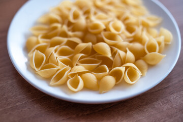 Close up of dried conchiglie pasta on a white plate. Intentional close focus, shallow depth of field and bokeh