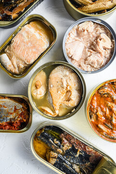 Set aluminium and tin cans with  Saury, mackerel, sprats, sardines, pilchard, squid, tuna over white textured background close up vertical