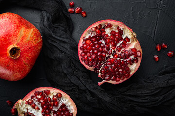 Ripe pomegranate with fresh juicy seeds, on black textured background, flat lay