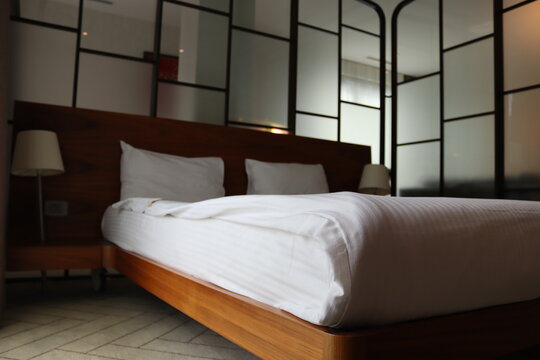 Bedroom with glass walls and double bed. Bed with wooden sides.