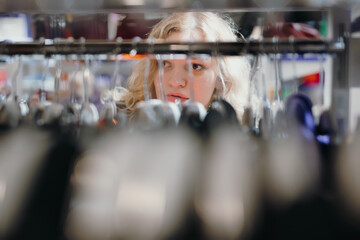 Woman customer choose clothes from the rack with hangers