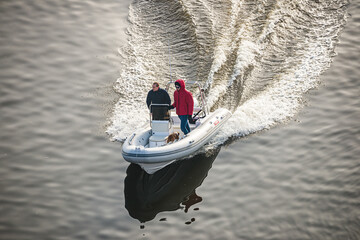Prague, Czech republic - February 24, 2021. Speed white dinghy boat with two man on board in Winter