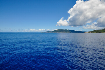 Tropical island on the ocean with white clouds and blue sky