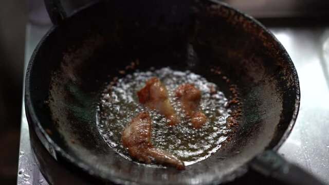 chicken meat cooking in hot oil on pan, unhealthy of fatty to people, splash and droplet of oil danger, gas fuel burnning to heat for fried or roast meat, raw fried chicken drumstick menu of delicious