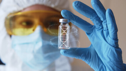 Young woman in eyeglasses and face mask with gloves holding test tube with 3d model of human DNA. Health care concept. Infecting process. Female doctor scientist searching for medical innovation