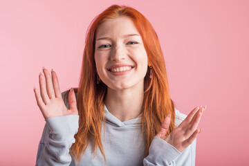Excited redhead girl in studio on pink background
