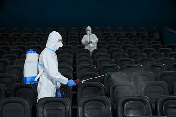 Workers cleaning cinema hall with special disinfectants.