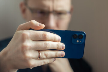 a man holds a smartphone horizontally in his hand. the hand is in focus, the man is blurred in the background