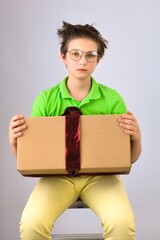 Boy in a bad mood holds a gift cardboard box brought from a warehouse.