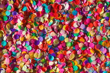 Fototapeta na wymiar Carnival confetti background, basis for a festive design or a postcard. Colored circles from paper, sunlight