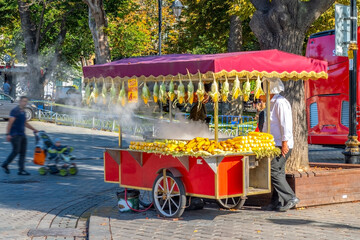 Naklejka premium A vendor sells fresh cooked corn on the cob in the Sultanahmet Square district of Istanbul Turkey, as a man with a stroller passes by.