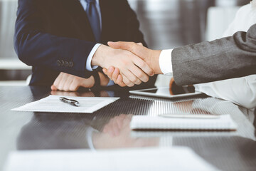 Handshake as successful negotiation ending, close-up. Unknown business people shaking hands after contract signing in modern office
