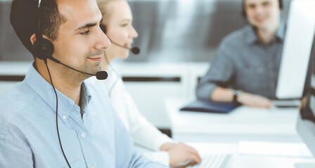 Obraz premium Call center. Group of casual dressed operators at work. Adult businessman in headset at customer service office. Telesales in business
