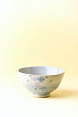 Traditional ceramic bowl on yellow background. Close up. Copy space.