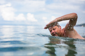 Senior man swimming in the Sea/Ocean - enjoying active retirement, having fun, taking care of...