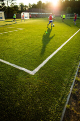 Soccer players on a pitch having match, lit by warm evening sun