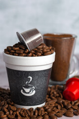 Distintos tipos de cafe, crudo, tostado, molido y en capsulas en varios recipientes.