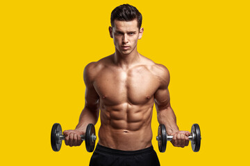 Fototapeta na wymiar Strong young man with bare torso, training with dumb-bell, showing six pack abs, isolated yellow background.