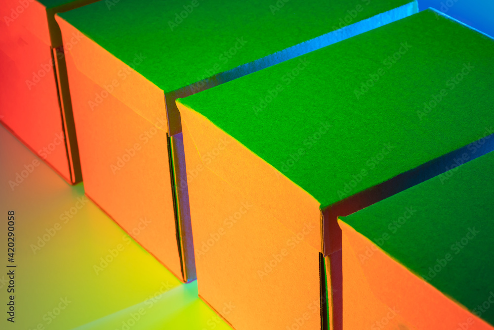 Poster cardboard boxes for shipping. several parcels are in a row. they are lit in neon light. concept - pr