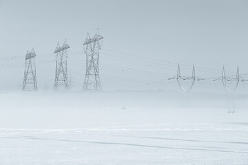 View of power line towers in fields with base shrouded in fog during a beautiful late winter early...