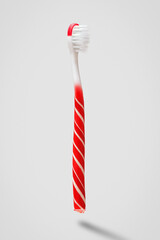 Creative concept of oral hygiene. Toothbrush in the shape of a lollipop on a gray background.