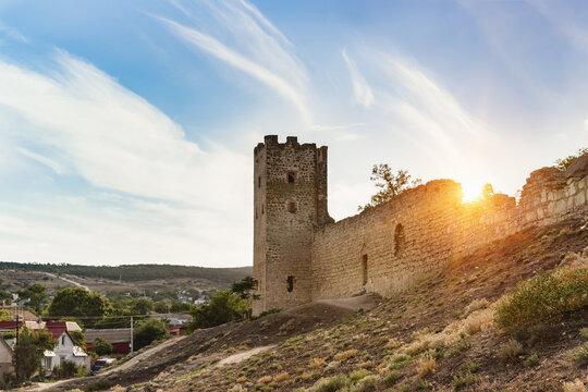 View from the shore of the Gulf of Feodosia to the defensive tower of Clement of the medieval fortress Kafa and the city of Feodosia. Sunset