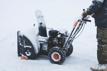 a man removes snow with a snow plow after a heavy snowfall near his house