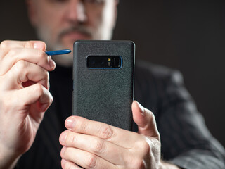 Man holds a smartphone in front of him. Concept businessman makes a video call. Video communication for business activities. Video call to a business partner. Blurred businessman in the background