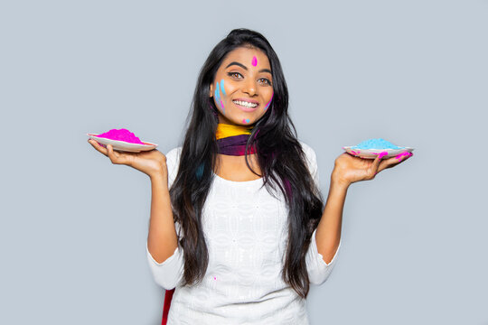 cheerful happy Indian woman in traditional Hindu dress woman holding powdered color in plate on the occasion of Holi festival. isolated over gray background