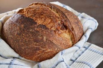 Freshly baked loaf of sourdough bread on a kitchen towel