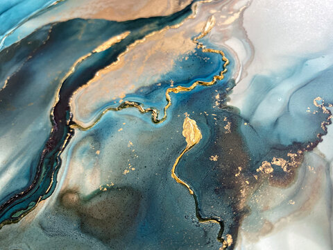 Abstract blue-green background with gold and beautiful smudges made with alcohol ink and golden acrylic. Fragment of art with turquoise texture resembles watercolor or aquarelle painting.