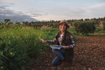 Female field engineer using a note book in agricultural plantation. Integration of women in the field, agriculture and happy women concepts