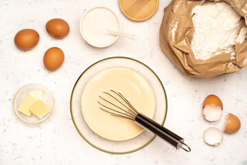 the process of making dough for pancakes with ingredients on a light table, eggs and flour are whipped with a mixer